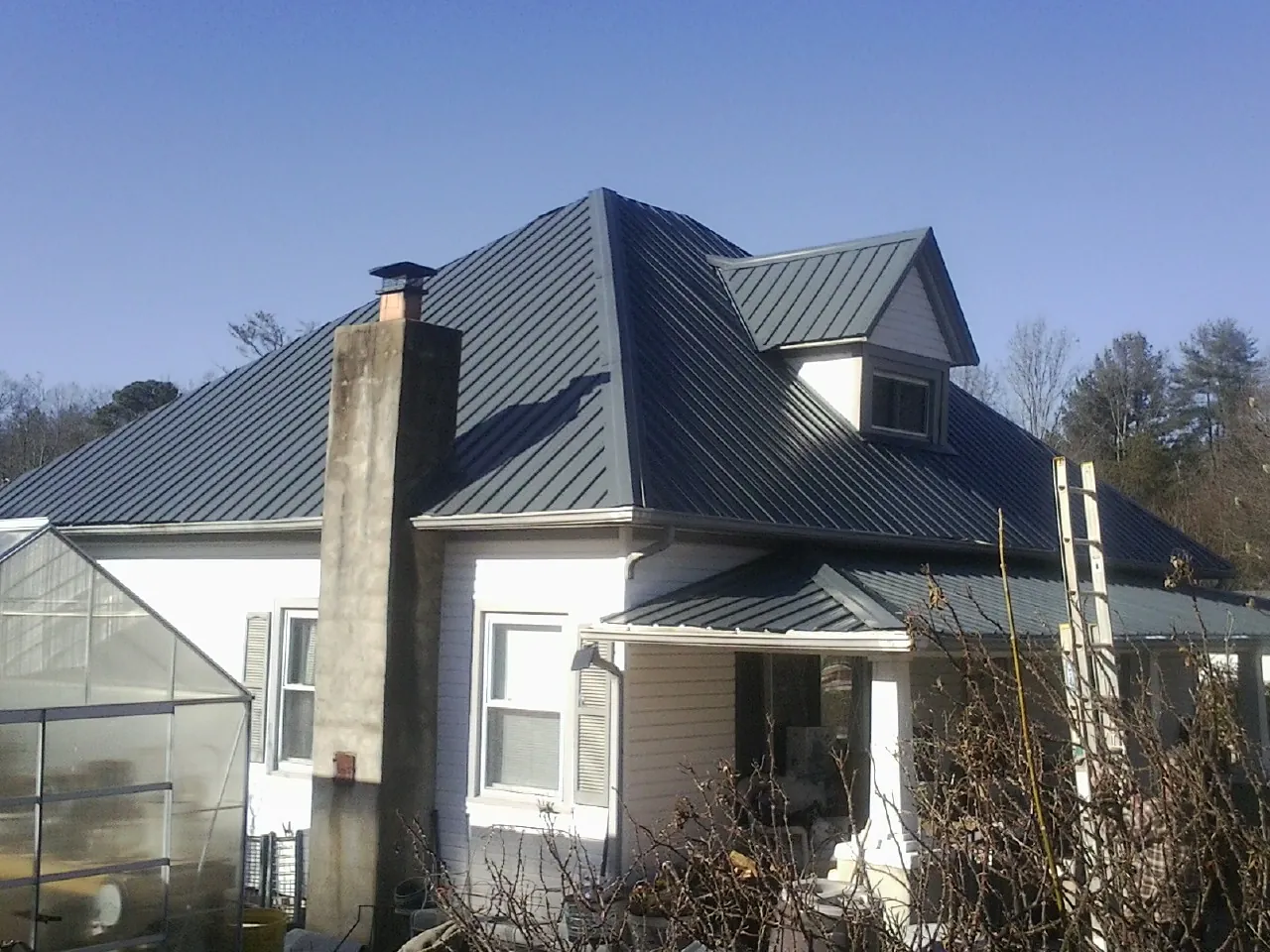 Dark blue standing seam metal roof on a white farmhouse with dormer — Slate & Tile Roof Repair by Roofing Brothers in Hopatcong