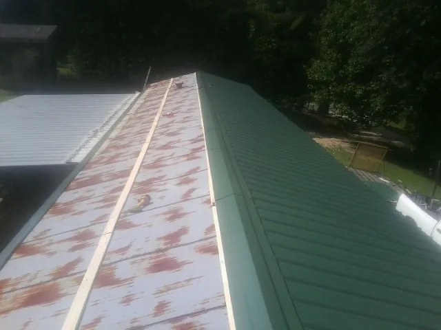 Old rusted panels beside newly installed green metal roofing — Wind Damage Roof Repair by Roofing Brothers in Hopatcong