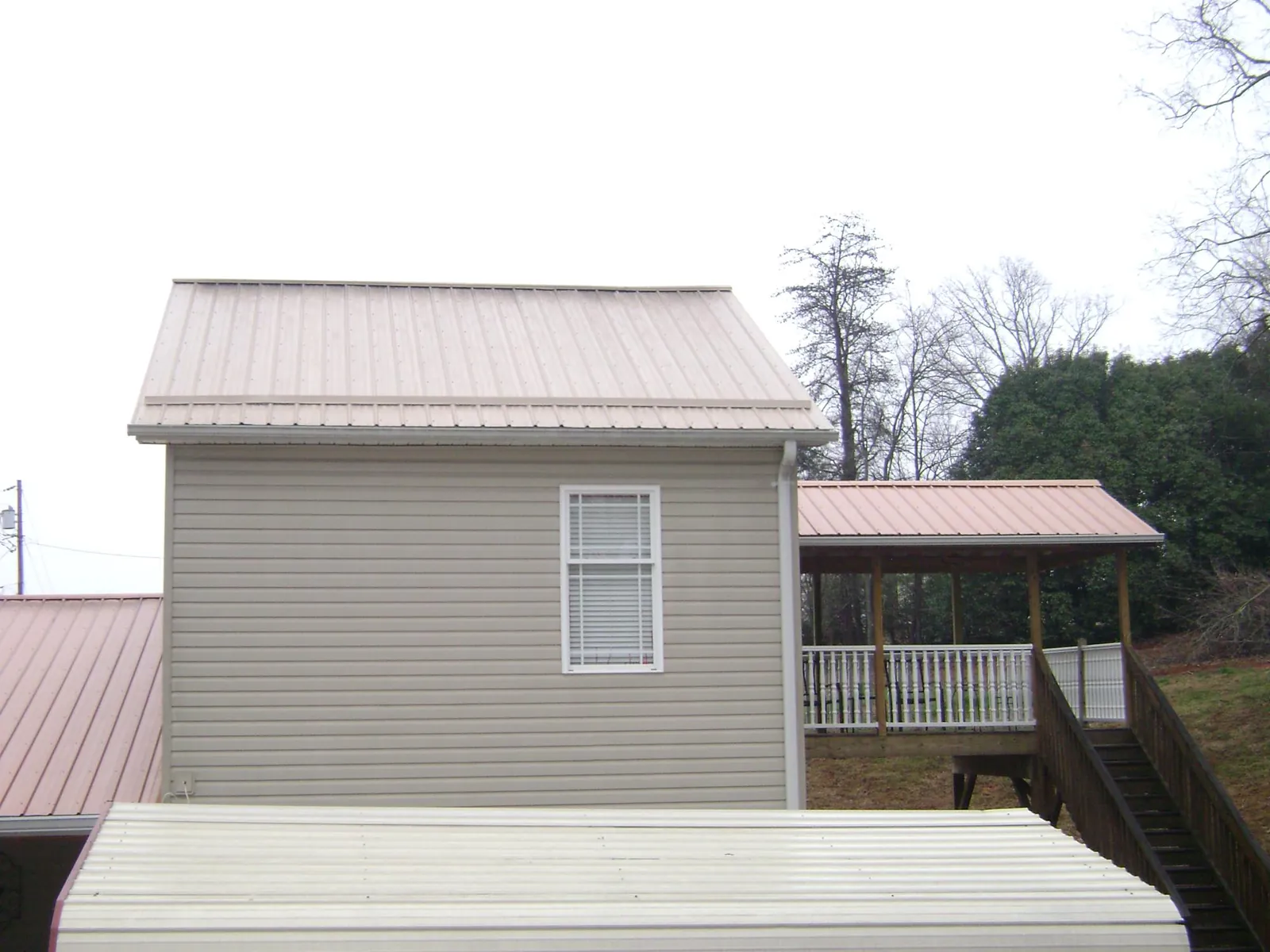 Tan metal roofs on a two story addition and attached porch, from a Roof Replacement job in Hopatcong