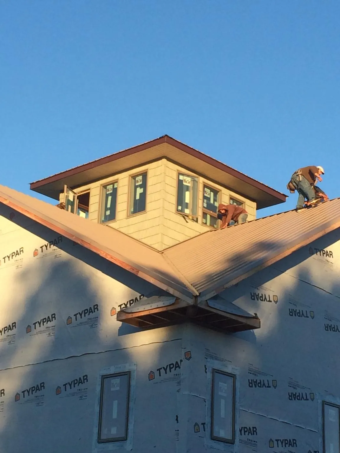 Roofers working around a rooftop cupola on a new metal roof at sunset — Roof Waterproofing in Hopatcong by Roofing Brothers